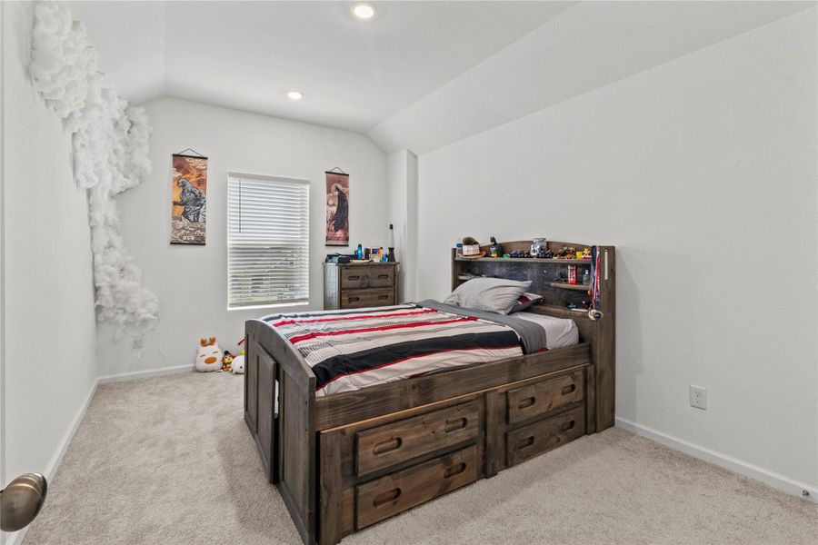 Cozy bedroom with carpet flooring, and bright natural light from a central window. Cozy bedroom with carpet flooring, and bright natural light from a central window.