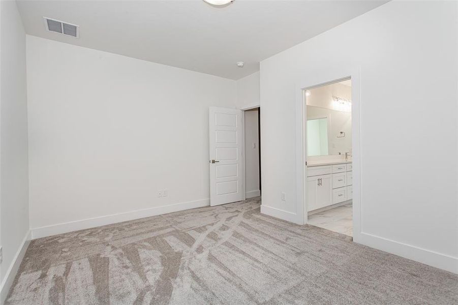 Unfurnished bedroom featuring connected bathroom and light carpet