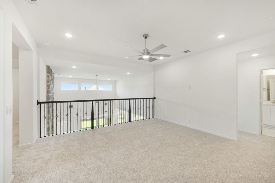 Open upstairs loft with carpet, ceiling fan, black iron railing, and recessed lighting overlooking lower level.