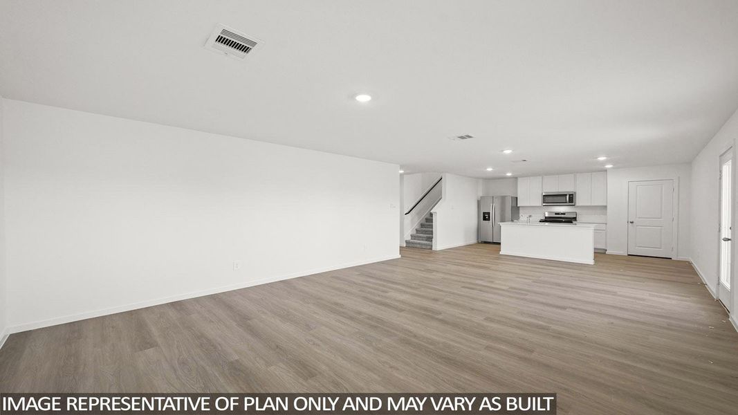 An open-concept living space with resilient flooring transitions seamlessly into a well-appointed kitchen.