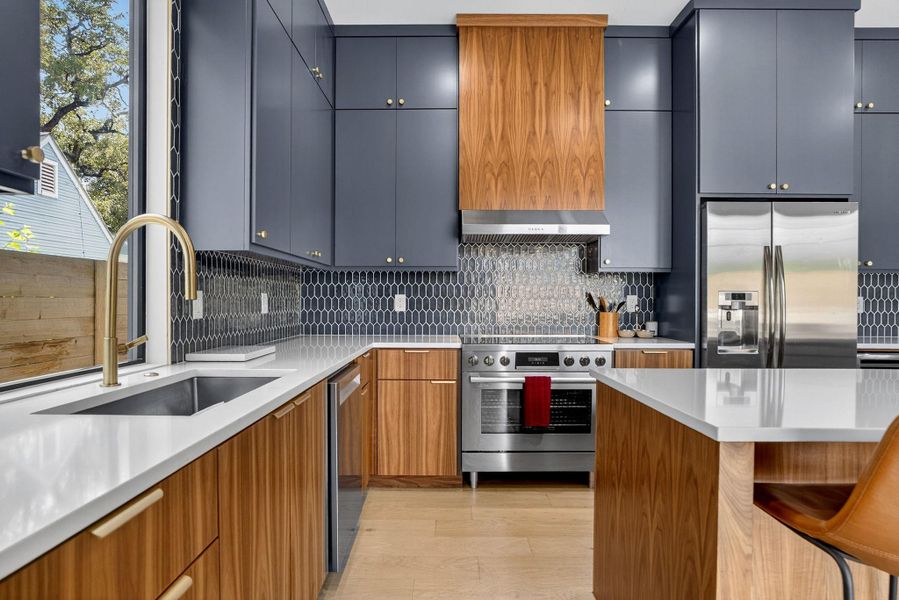 Kitchen with appliances with stainless steel finishes, light wood-type flooring, tasteful backsplash, a kitchen breakfast bar, and brown cabinetry