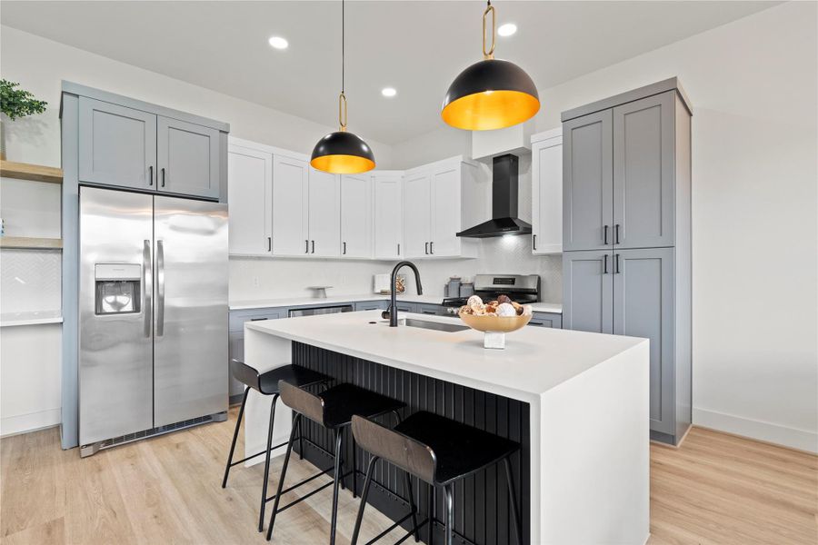 Modern pendant lighting with brass interiors brings warmth and dimension to the kitchen’s sleek lines.