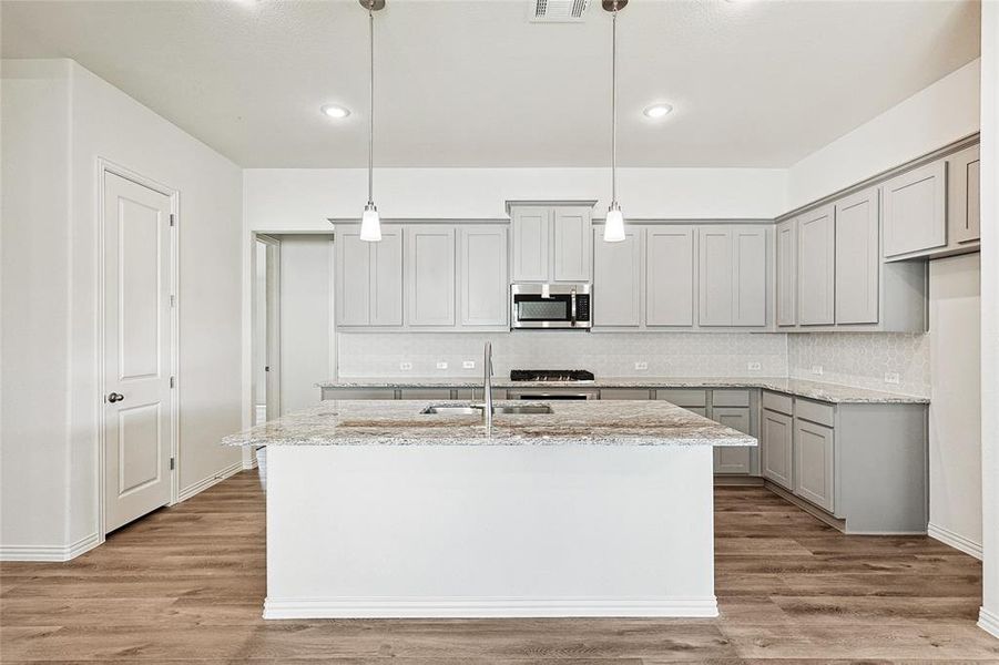 Kitchen with pendant lighting, a kitchen island with sink, and stainless steel appliances