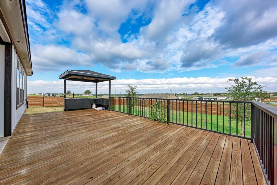 A spacious wooden deck features secure metal railings and overlooks an expansive grassy yard. A spacious wooden deck features secure metal railings and overlooks an expansive grassy yard.