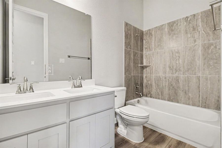 Bathroom featuring a double vanity with white cabinetry, dual sinks, and a large mirror Bathroom featuring a double vanity with white cabinetry, dual sinks, and a large mirror