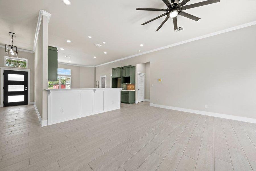 Unfurnished living room featuring ornamental molding, a ceiling fan, baseboards, recessed lighting, and light wood-type flooring Unfurnished living room featuring ornamental molding, a ceiling fan, baseboards, recessed lighting, and light wood-type flooring