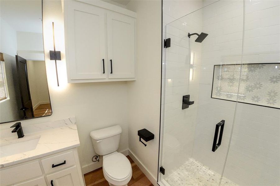 Full bath featuring vanity, a stall shower, and wood finished floors