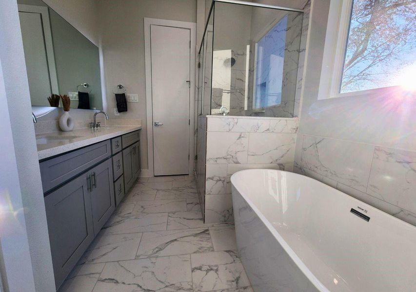 This bathroom features a modern design with a spacious freestanding tub, glass-enclosed shower, and dual-sink vanity. It's accented with elegant marble tiles and ample natural light. This bathroom features a modern design with a spacious freestanding tub, glass-enclosed shower, and dual-sink vanity. It's accented with elegant marble tiles and ample natural light.