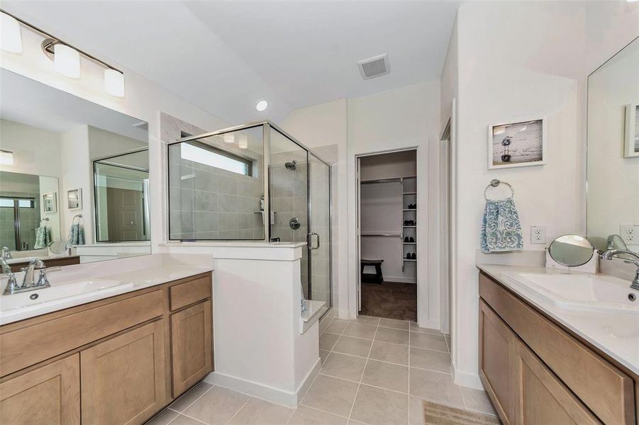 Bathroom featuring vanity, walk in shower, and tile patterned flooring