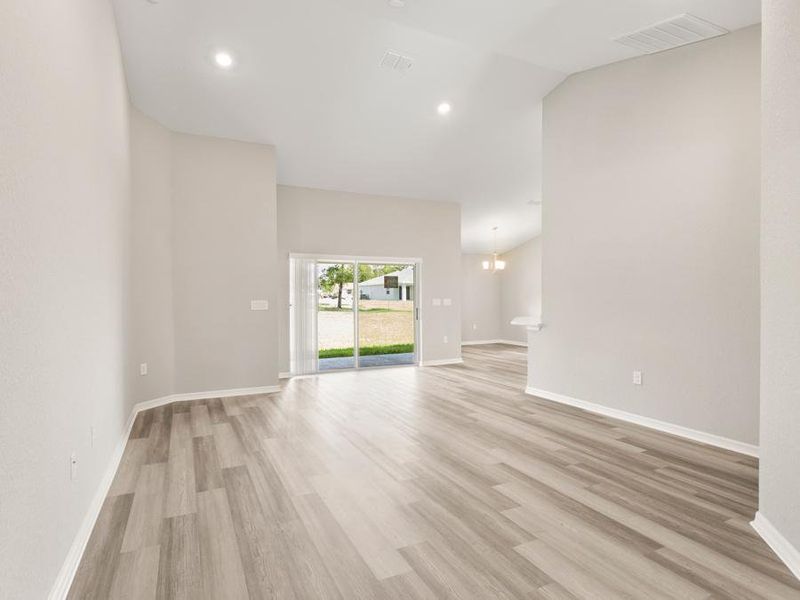 Enjoy a sunny living area with volume ceilings and luxury vinyl plank flooring.