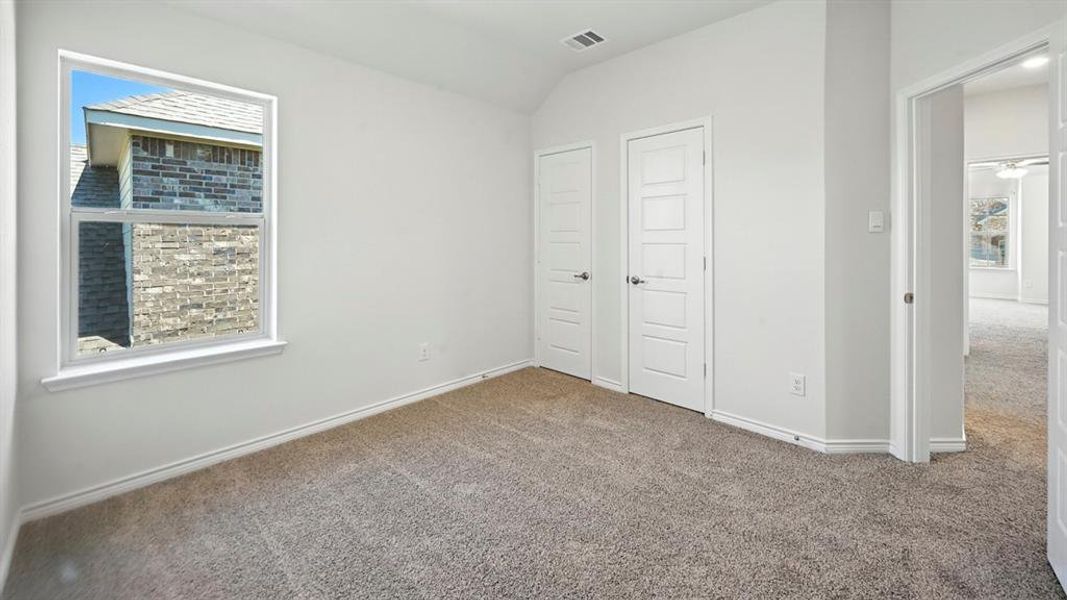 Unfurnished bedroom with carpet floors, a closet, and vaulted ceiling