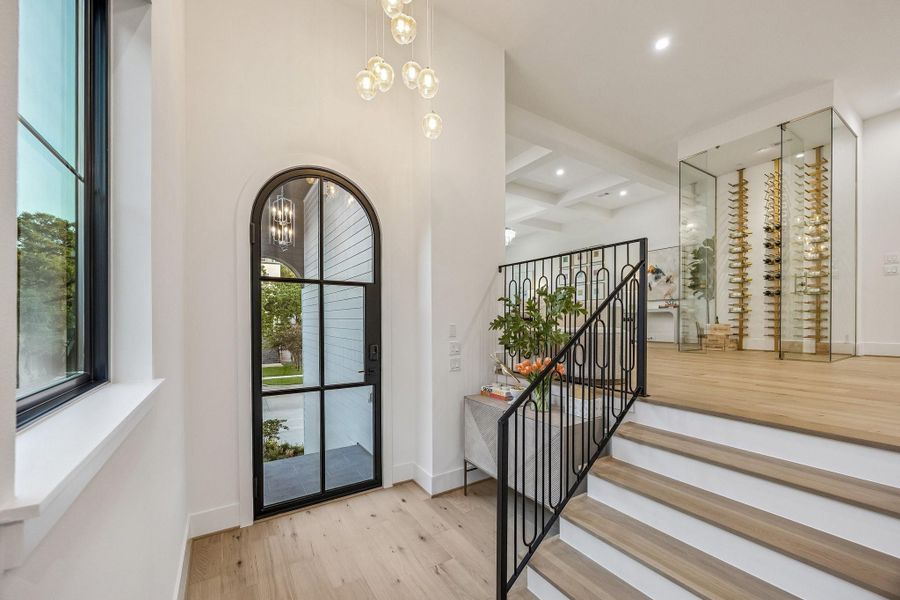 Another view of the formal entrance of the home. The space is defined by soaring ceilings and an abundance of natural light streaming in through the large black-framed iron glass door with 6 divided lite windows, creating a bright and welcoming atmosphere. Another view of the formal entrance of the home. The space is defined by soaring ceilings and an abundance of natural light streaming in through the large black-framed iron glass door with 6 divided lite windows, creating a bright and welcoming atmosphere.