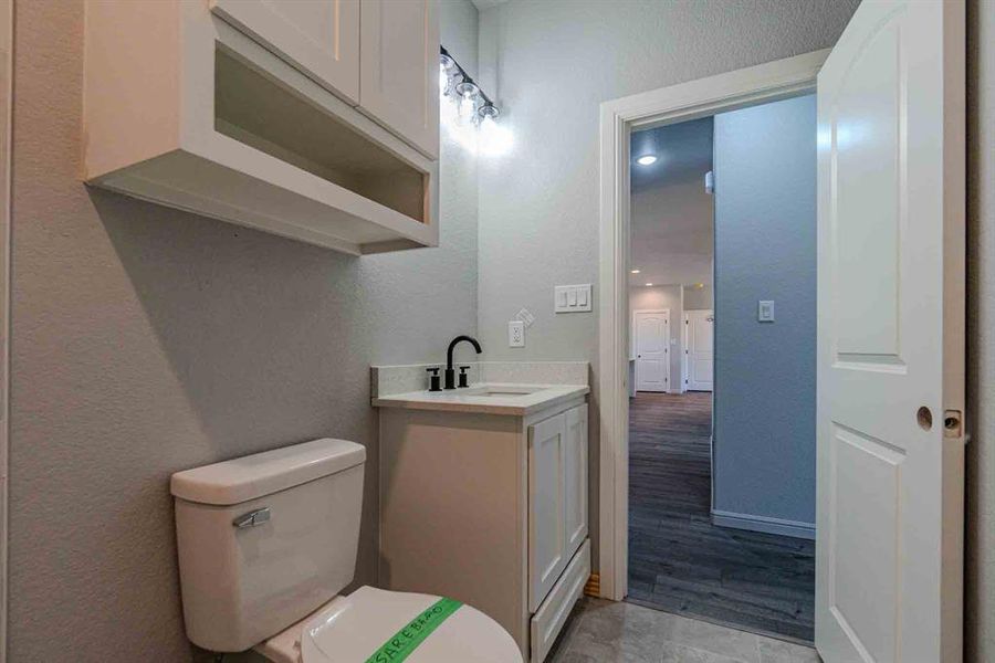 Half bathroom with a textured wall and vanity Half bathroom with a textured wall and vanity
