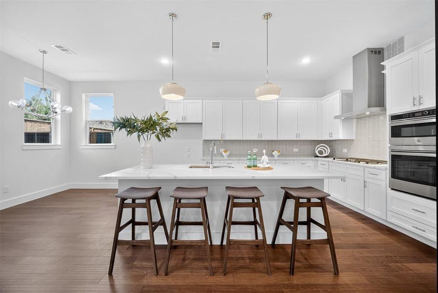 Kitchen featuring decorative backsplash, a breakfast bar, dark wood-style floors, and white cabinets