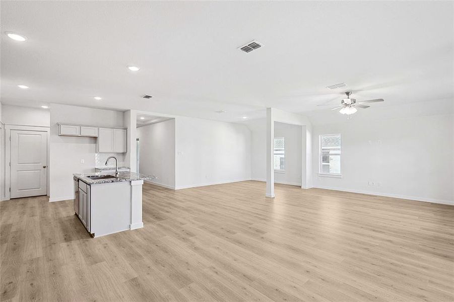 Unfurnished living room with light hardwood / wood-style floors, sink, and ceiling fan