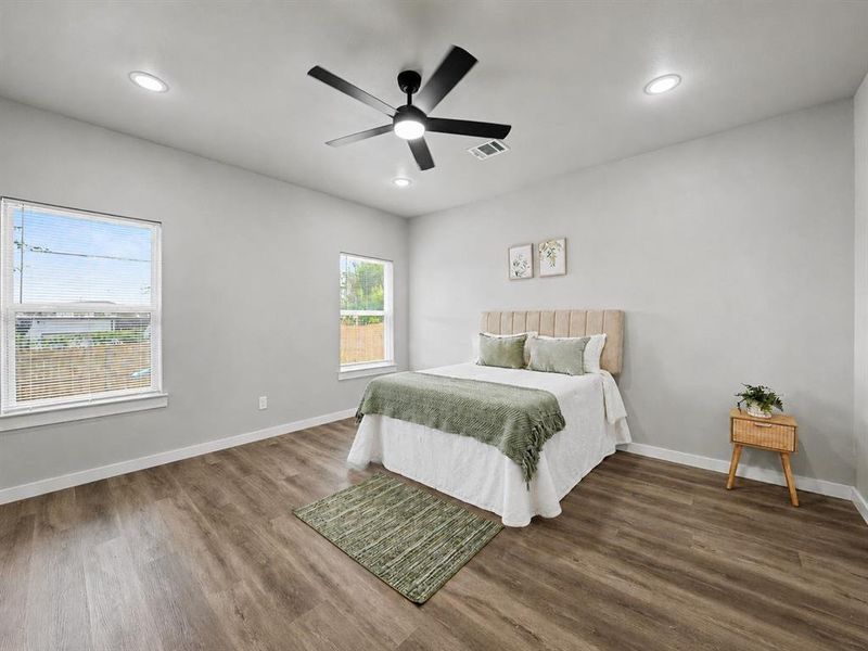 Spacious room featuring wood-finish flooring, light grey walls, and a contemporary ceiling fan with integrated lighting Spacious room featuring wood-finish flooring, light grey walls, and a contemporary ceiling fan with integrated lighting