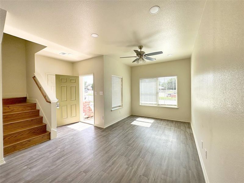 Unfurnished living room featuring stairway, wood finished floors, a textured ceiling, recessed lighting, and ceiling fan