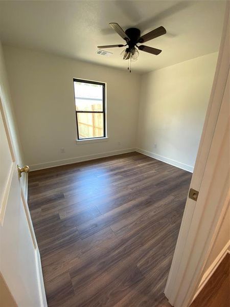 Empty room featuring ceiling fan and dark wood-type flooring