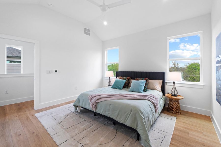 High vaulted ceilings and rich hardwood flooring define this serene, window-lit bedroom space.