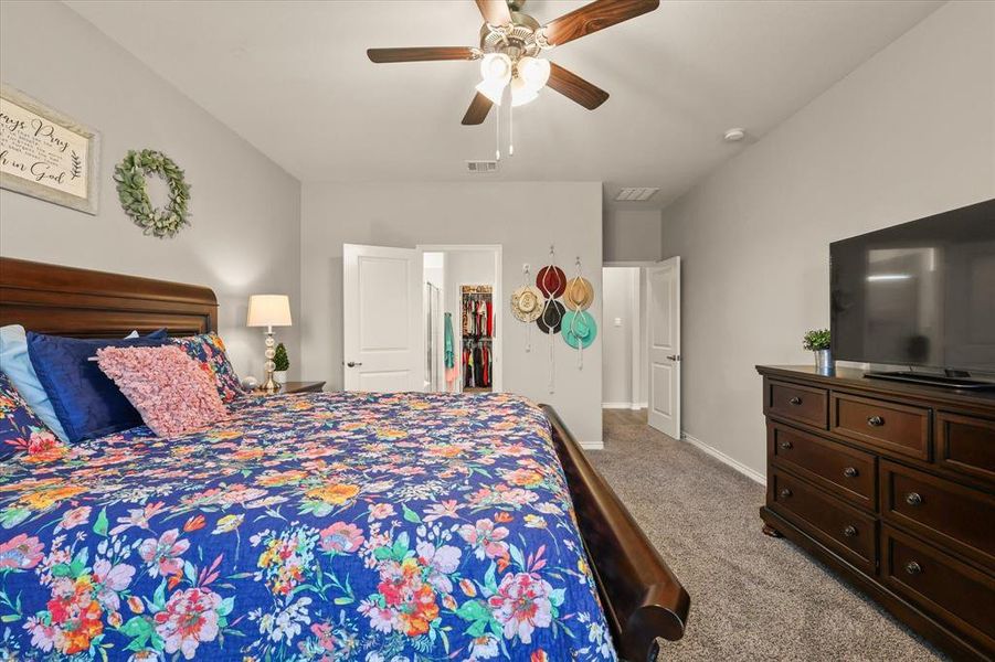 Carpeted bedroom featuring a spacious closet and ceiling fan Carpeted bedroom featuring a spacious closet and ceiling fan