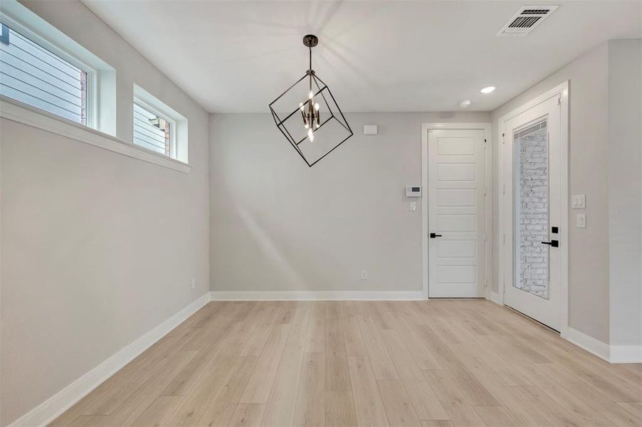 Unfurnished dining area with a chandelier and light wood finished floors