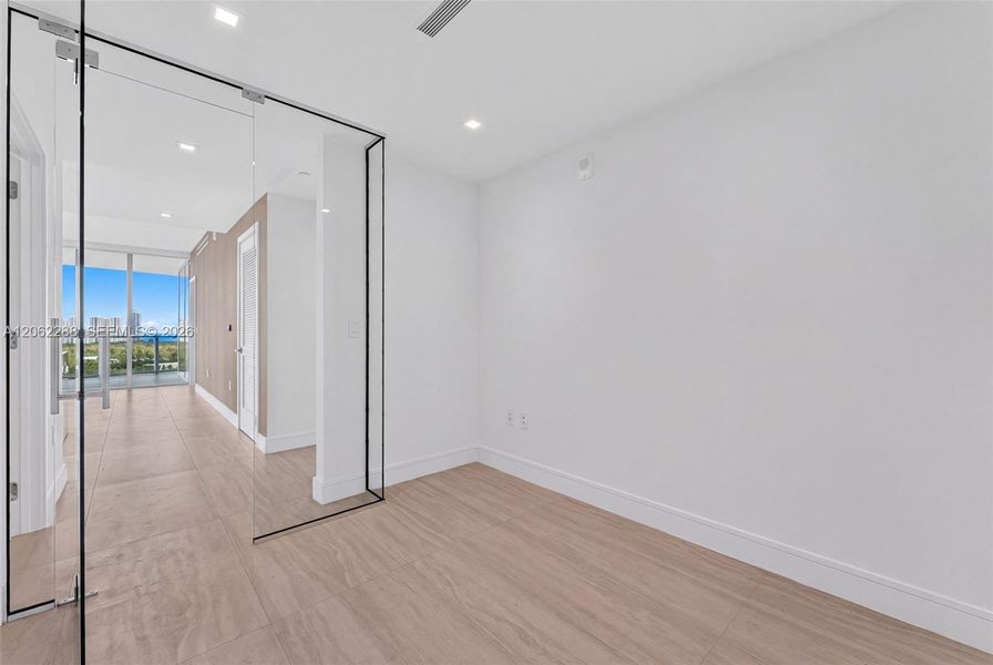 Floor-to-ceiling glass enclosure with black metal frame, wood-finish flooring, recessed lighting, and wall-to-wall windows