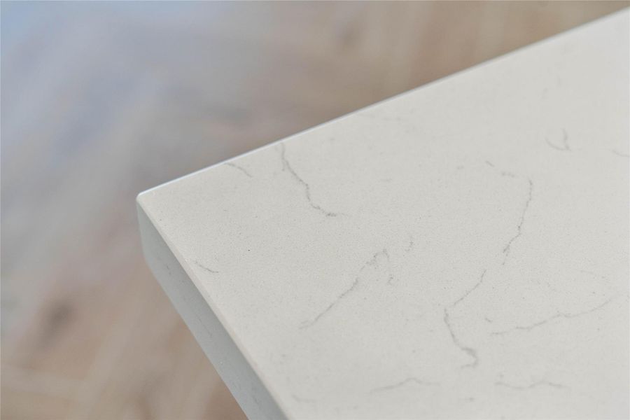 This sophisticated quartz countertop features a luminous white base accented by subtle, organic grey veining that elegantly emulates high-end natural marble