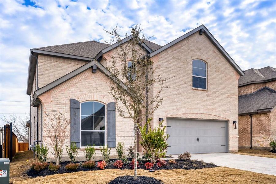 French country home featuring an attached garage, brick siding, concrete driveway, and a shingled roof