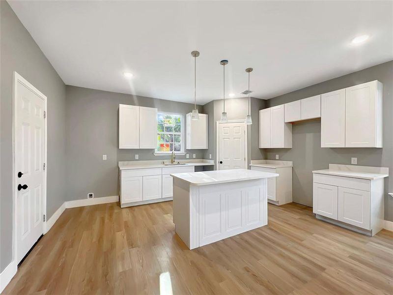 Kitchen featuring white cabinets, light hardwood / wood-style flooring, a kitchen island, and sink