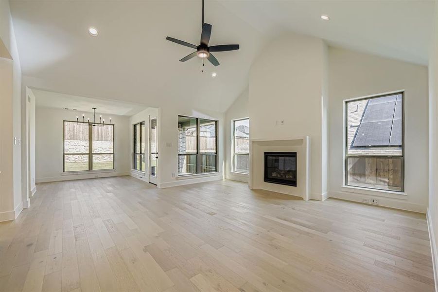 Unfurnished living room featuring a high ceiling, suspended lighting, healthy amount of natural light, and ceiling fan