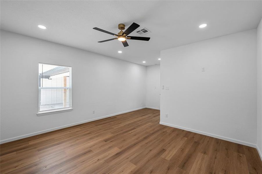 Open-concept room featuring wood-finish flooring, white walls, and a contemporary ceiling fan Open-concept room featuring wood-finish flooring, white walls, and a contemporary ceiling fan