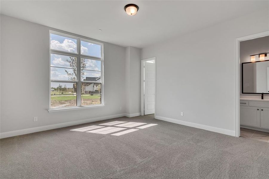 Unfurnished bedroom with multiple windows, light carpet, and ensuite bathroom