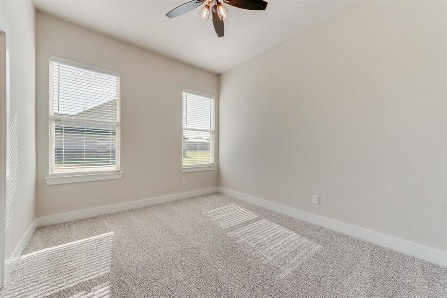 Carpeted spare room featuring ceiling fan