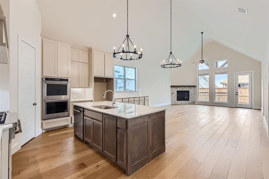 Kitchen with appliances with stainless steel finishes, high vaulted ceiling, a fireplace, decorative light fixtures, and sink