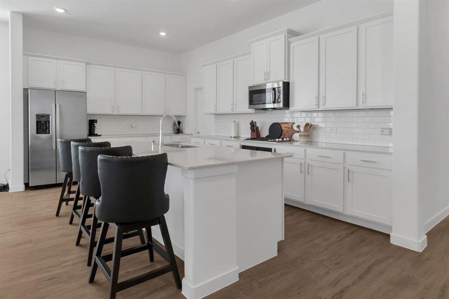 Kitchen featuring white cabinetry, a kitchen breakfast bar, appliances with stainless steel finishes, dark wood-style flooring, and recessed lighting