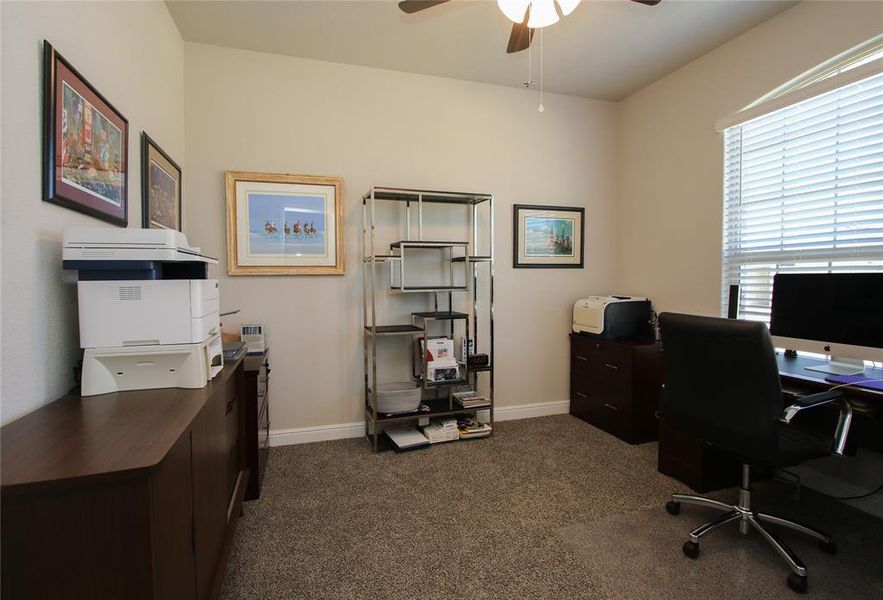 Home office with ceiling fan and carpet