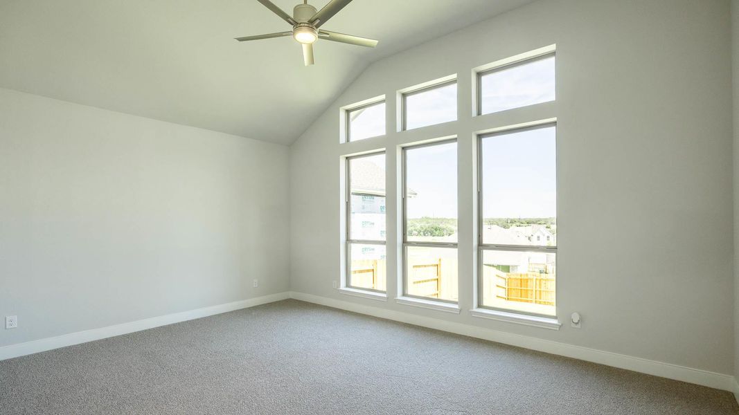 Unfurnished room with carpet floors, lofted ceiling, baseboards, and ceiling fan Unfurnished room with carpet floors, lofted ceiling, baseboards, and ceiling fan
