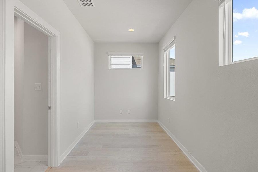 Hall with light wood-style floors and recessed lighting