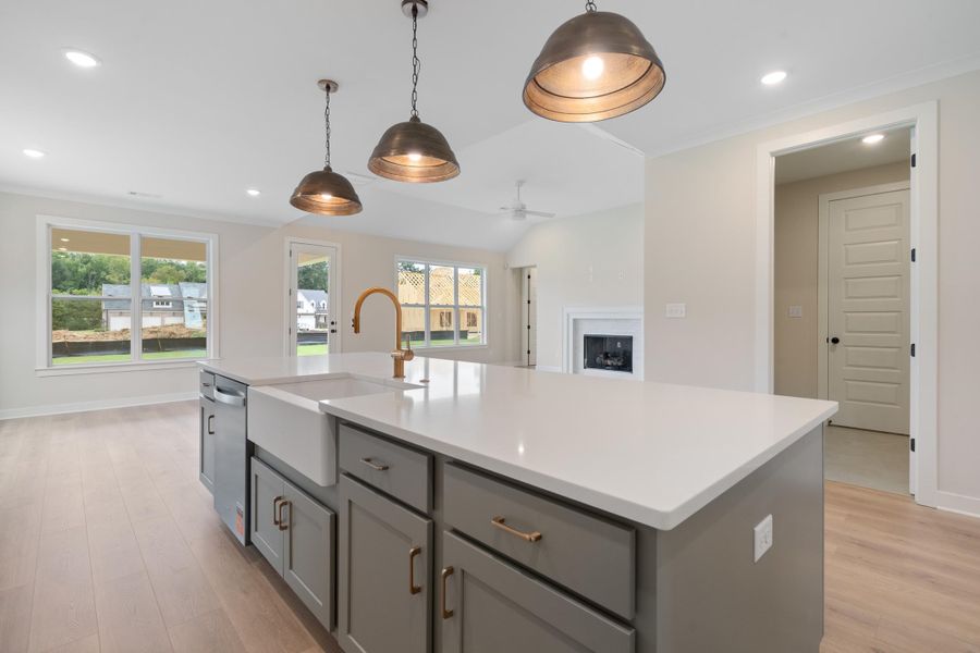 Kitchen island featuring a white farmhouse sink, brass-finish faucet, and integrated dishwasher Kitchen island featuring a white farmhouse sink, brass-finish faucet, and integrated dishwasher