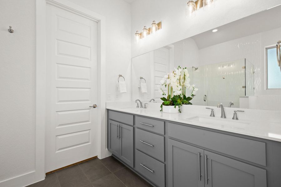 Full bathroom featuring a stall shower, dark tile patterned floors, and double vanity