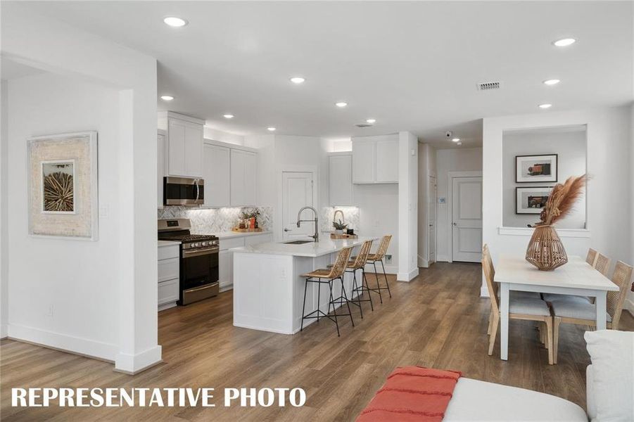 Kitchen with stainless steel appliances, an island with sink, cabinetry, and backsplash