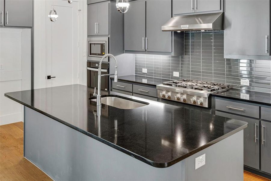 Kitchen with under cabinet range hood, light wood-style flooring, stainless steel appliances, and a sink