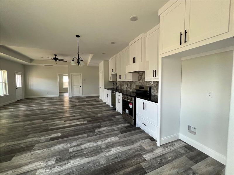 Kitchen with a sink, stainless steel appliances, white cabinets, dark countertops, and tasteful backsplash