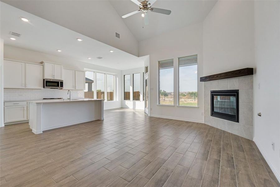 Kitchen featuring white cabinetry, a fireplace, high vaulted ceiling, and light hardwood / wood-style flooring