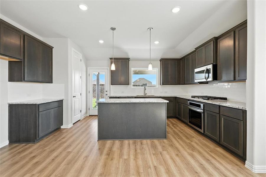 Kitchen with appliances with stainless steel finishes, dark brown cabinets, tasteful backsplash, and recessed lighting Kitchen with appliances with stainless steel finishes, dark brown cabinets, tasteful backsplash, and recessed lighting