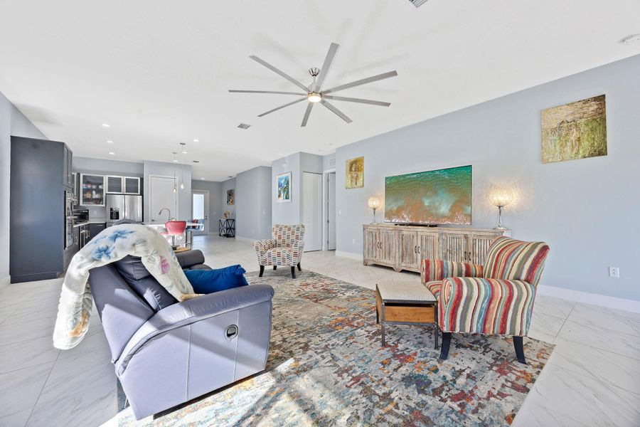 Living area with recessed lighting, light marble finish floors, and a ceiling fan