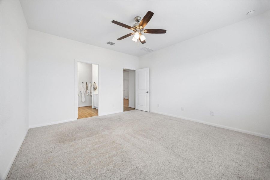 Unfurnished bedroom with ceiling fan, light colored carpet, and ensuite bath
