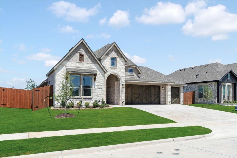 Single-story home with stone and brick exterior, two-car garage, and manicured front lawn