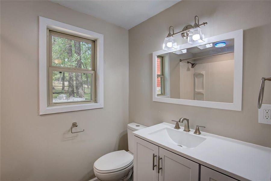 Bathroom featuring walk in shower, vanity, and toilet