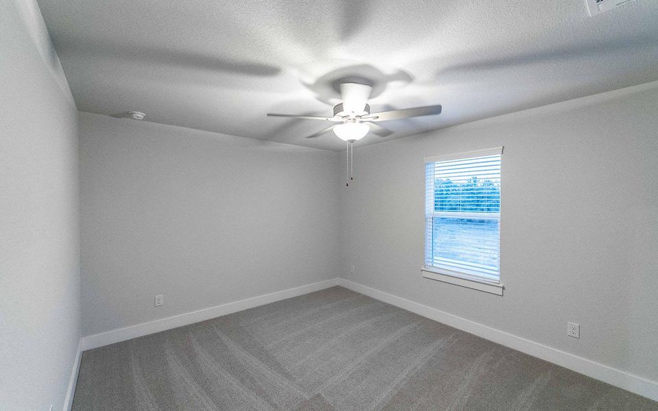 Carpeted empty room with ceiling fan, a textured ceiling, and baseboards